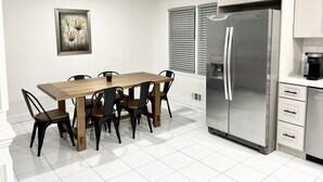 A modern kitchen with white cabinetry, a stainless steel refrigerator, and a wooden dining table with chairs. - Cozy Home 10 minutes from downtown Norcross and 25 minutes from downtown Atlanta (Norcross)