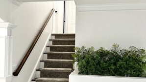A staircase with a wooden handrail and carpeted steps, leading to a white door. - Cozy Home 10 minutes from downtown Norcross and 25 minutes from downtown Atlanta (Norcross)
