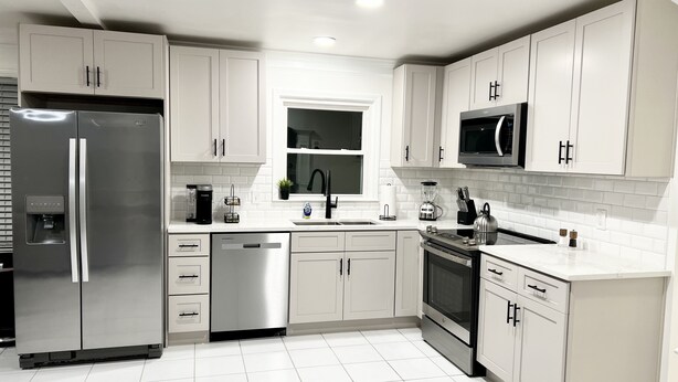 A modern kitchen with white cabinetry, stainless steel appliances, and a tiled floor. - Cozy Home 10 minutes from downtown Norcross and 25 minutes from downtown Atlanta (Norcross)