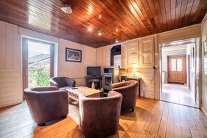 Ein gemütliches Zimmer mit Holzboden, Kamin und Essbereich mit Tisch und Stühlen.