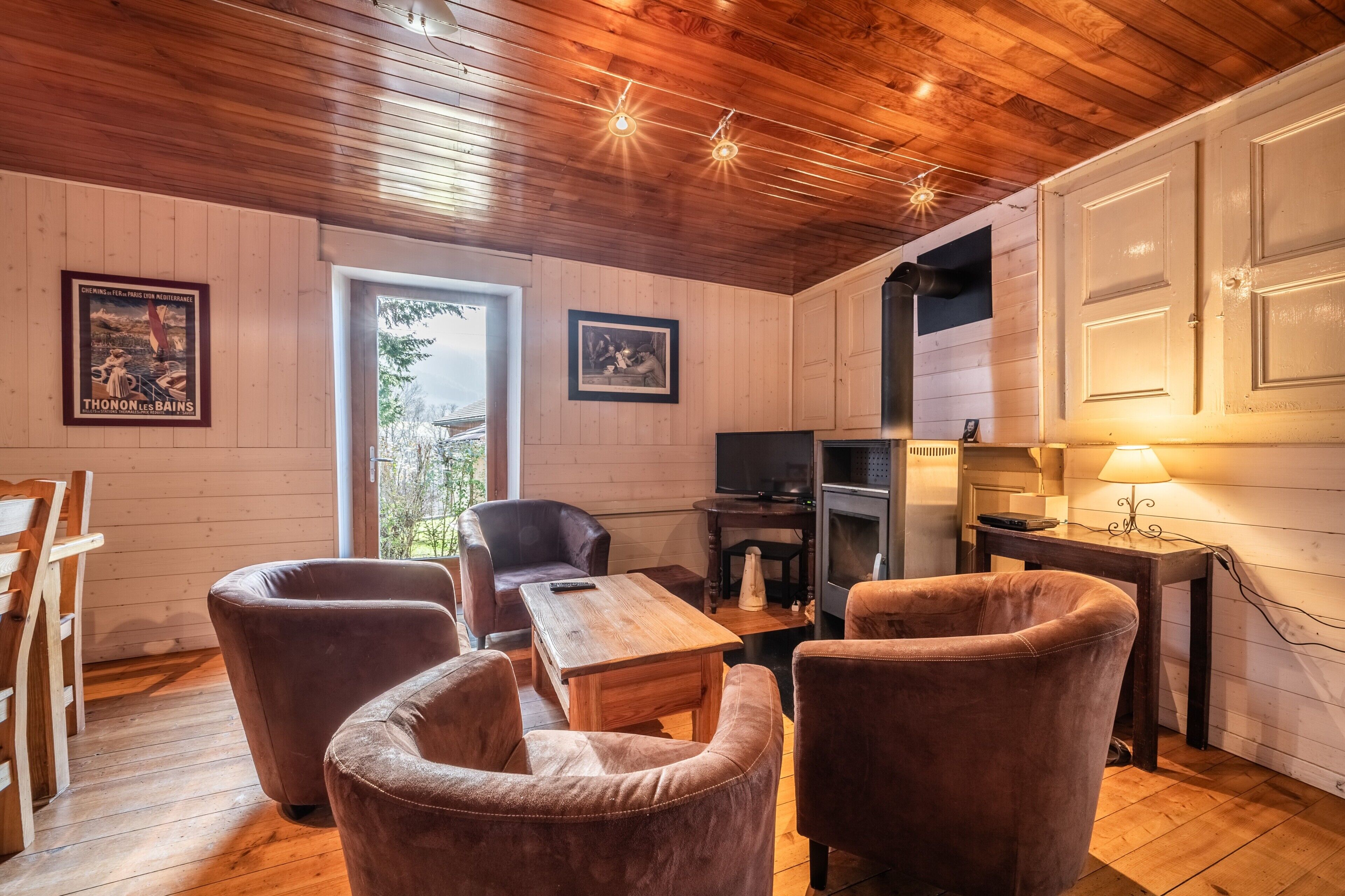 Une pièce chaleureuse avec un plancher en bois, une cheminée, un téléviseur et une table à manger.