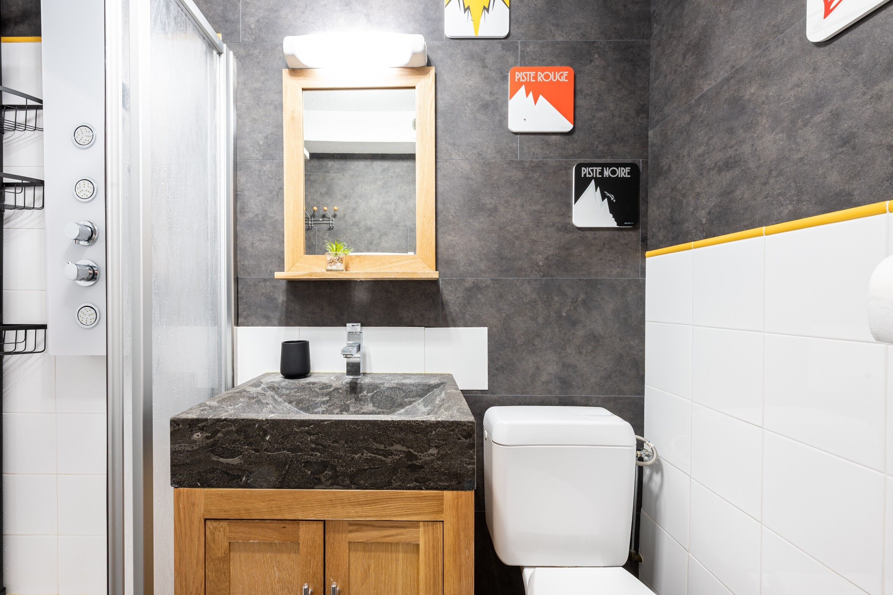 A modern bathroom with a marble sink, wooden cabinet, and a white toilet.