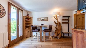 A wooden interior with a dining table, chairs, a lamp, a wooden cabinet, and a large tree trunk decoration. - Apartment 'Victorsun2' with Mountain View, Terrace and Private Garden (la clusaz)