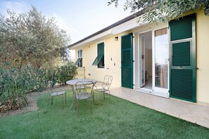 Een gebouw met een terras, een tafel en stoelen.