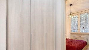Una camera da letto con un letto, una finestra con tende, un termosifone e una lampada a sospensione.