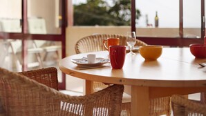 A round wooden table with wicker chairs, a glass of wine, and a few cups.
