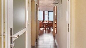 A hallway with a dining area at the end, featuring a table and chairs.