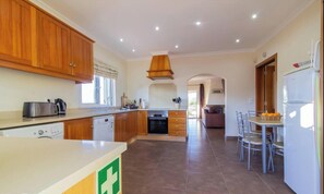 Una cucina con mobili in legno, lavastoviglie, piano cottura e un'area pranzo con sedie e tavolo.