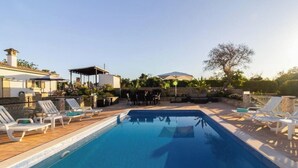 A swimming pool with lounge chairs, a covered seating area, and a stone wall. - Villa 'Peacehaven' with Mountain View, Wi-Fi and Air Conditioning (Loulé)