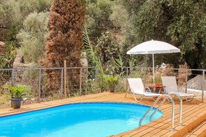 Un pontile in legno con piscina, sedie a sdraio e ombrellone.