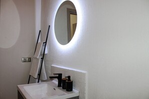 Une salle de bain avec un lavabo blanc, un miroir et un porte-serviettes.
