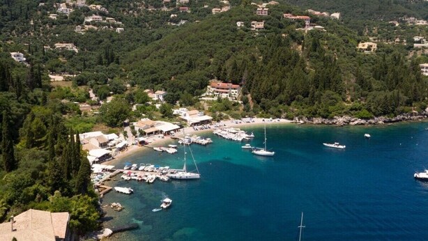 Un village côtier doté d’un port de plaisance, de maisons construites sur des collines et d’une eau d’un bleu cristallin.