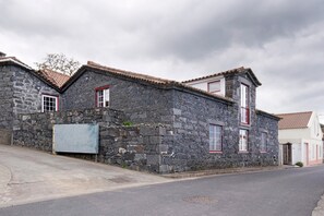 A stone building with red-framed windows and a tiled roof. - Holiday Home 'Ponta Da Amora' with Sea View, Wi-Fi and Air Conditioning (Ponta Garça)