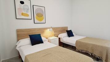 Une chambre d’hôtel avec deux lits, une table de chevet, une lampe et deux œuvres d’art encadrées accrochées au mur.