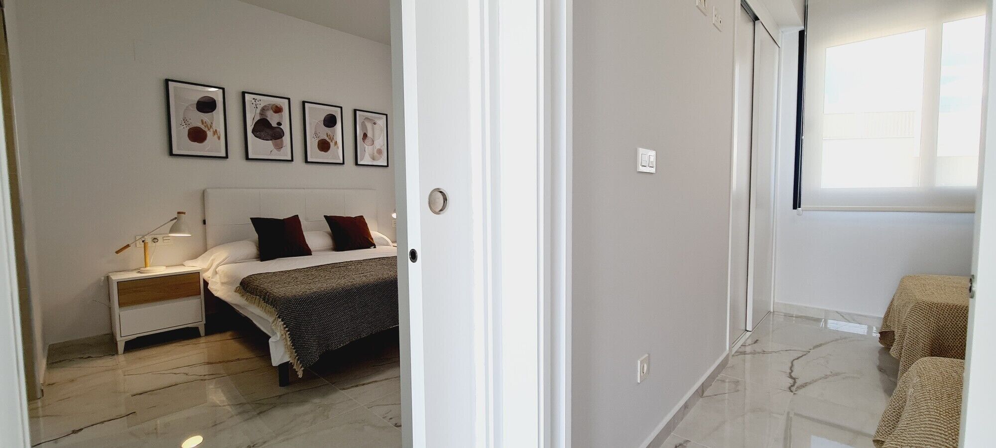 Une chambre à coucher avec un lit, une table de chevet, une lampe et des œuvres d’art murales.