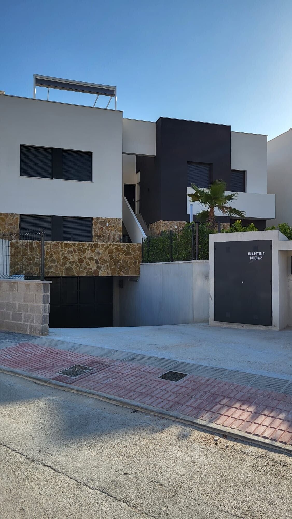 A modern building with a stone facade, a black garage door, and a staircase leading to an upper level.