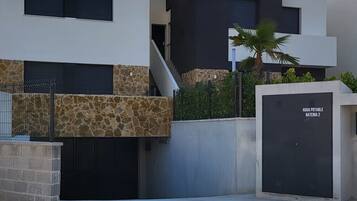 A modern building with a stone facade, a black garage door, and a staircase leading to an upper level.