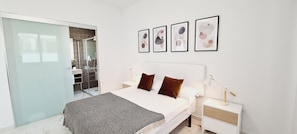 Un dormitorio moderno con cama, dos mesitas de noche, lámparas de noche y arte abstracto en la pared.