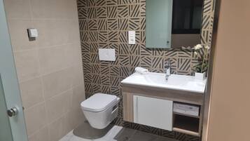 Un baño con pared estampada, inodoro blanco, lavamanos con espejo y un armario.