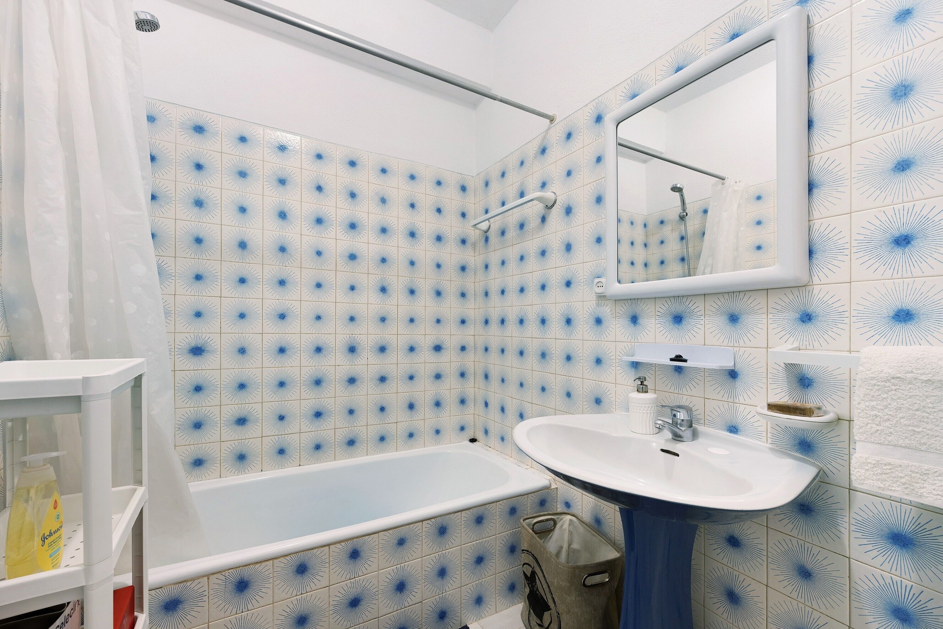 Een badkamer met een bad, een wastafel, een spiegel en een douchegordijn.