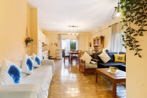A living room with a sofa, coffee table, and dining area with chairs.