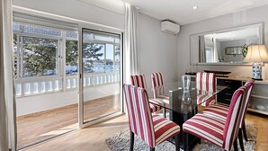 A modern dining area with a glass table, striped chairs, and a view through large windows. - Holiday Home 'Casa Vista Rio' with Sea View, Wi-Fi and Air Conditioning (Ferragudo)