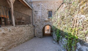 A stone building with a narrow passageway, a wooden door, and a metal railing. - Holiday Home 'Gîte La Voisine' with Private Terrace, Wi-Fi and Air Conditioning (Venteuil)