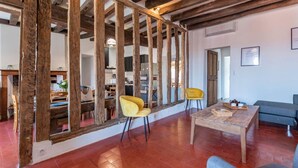 A rustic interior with exposed wooden beams, a dining area with chairs, and a sofa. - Holiday Home 'Gîte La Voisine' with Private Terrace, Wi-Fi and Air Conditioning (Venteuil)