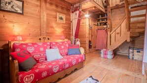 A wooden interior with a sofa, a staircase, and a red and white checkered curtain.