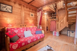 A wooden interior with a sofa, a staircase, and a red and white checkered curtain.