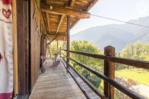 Un balcon en bois offrant une vue sur les montagnes et la verdure.