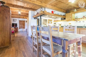 Un intérieur rustique en bois, comprenant un coin repas, un plafond en bois et une cuisine avec des armoires et des étagères en bois.
