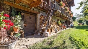 A wooden chalet with a balcony, potted plants, and a wooden staircase.