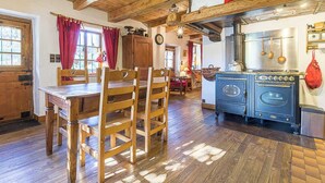 A rustic kitchen with wooden furniture, a vintage stove, and a dining area with a wooden table and chairs.