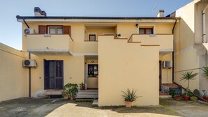 A two-story building with a balcony, potted plants, and an air conditioning unit. - Apartment 'Flamingo House' with Balcony, Wi-Fi and Air Conditioning (Cabras)