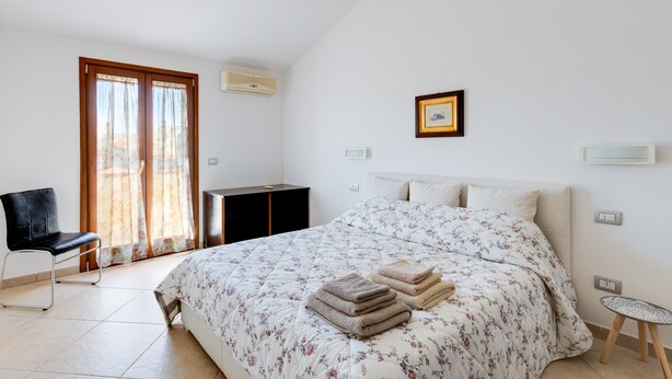 A bedroom with a bed, a chair, a desk, and a window with curtains. - Apartment 'Flamingo House' with Balcony, Wi-Fi and Air Conditioning (Cabras)