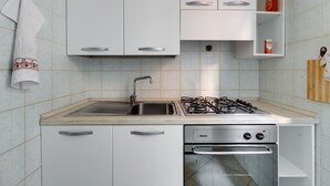 A kitchen with white cabinets, a stainless steel sink, a gas stove, and a built-in oven. - Apartment 'Flamingo House' with Balcony, Wi-Fi and Air Conditioning (Cabras)
