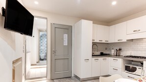 Una cucina moderna con mobili bianchi, un forno a microonde e un'area pranzo con un tavolo apparecchiato per due.