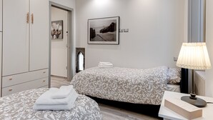 Camera da letto con due letti, un comodino, una lampada, un quadro appeso al muro e un armadio.