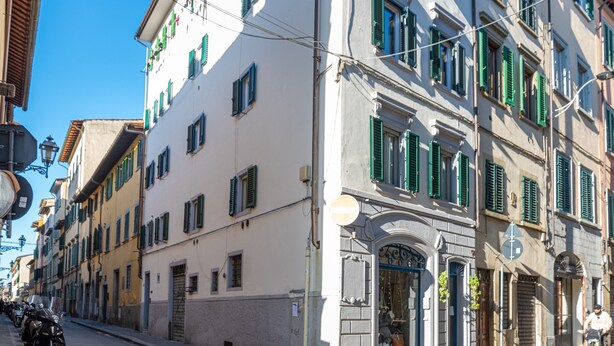 Una strada fiancheggiata da edifici, un cartello e scooter parcheggiati.