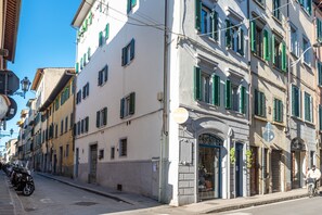 Une rue bordée d’immeubles, avec une enseigne et des scooters garés.