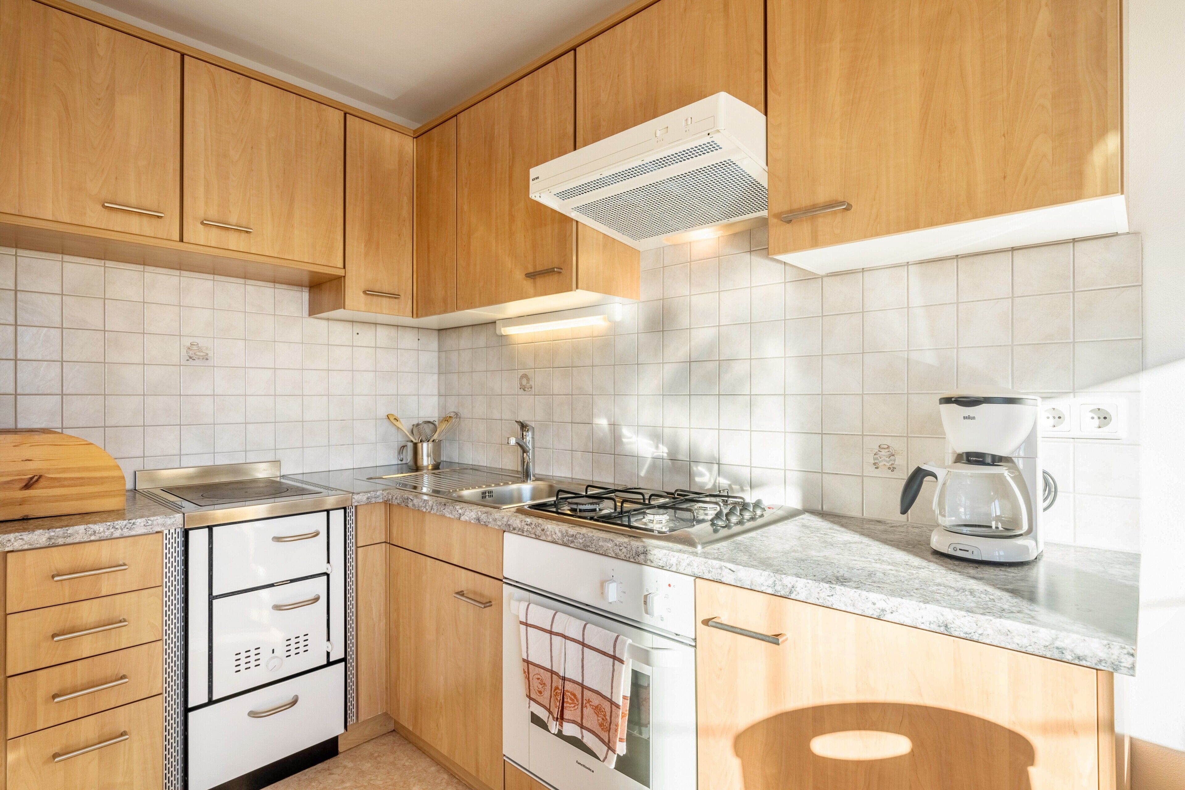 A kitchen with wooden cabinets, a stainless steel sink, a gas stove, an oven, and a coffee maker.