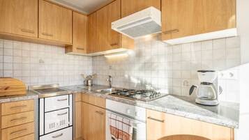 A kitchen with wooden cabinets, a stainless steel sink, a gas stove, an oven, and a coffee maker.