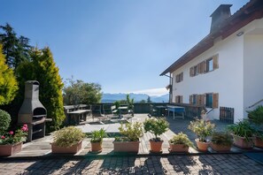 Une terrasse aménagée avec du mobilier d’extérieur, des plantes en pot et un four à bois.