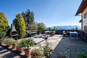 Une terrasse extérieure dotée d’un four à pizza, de sièges et de plantes en pot.