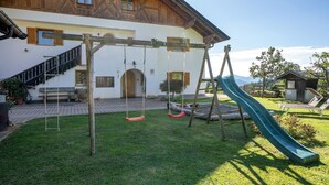 Une maison en bois avec une balançoire et un toboggan dans le jardin.