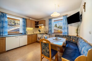 A compact kitchen with wooden cabinets, a dining table, and a sofa.