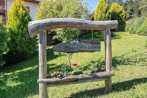 A rustic wooden signpost with a flower in a garden setting.