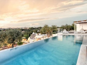 Une piscine offrant une vue sur le paysage urbain et les oliviers.