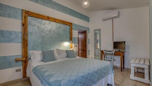 Un dormitorio con cama, escritorio, silla y televisor.
